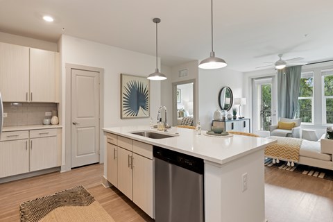 A modern kitchen with a large island and a dining area in the background.
