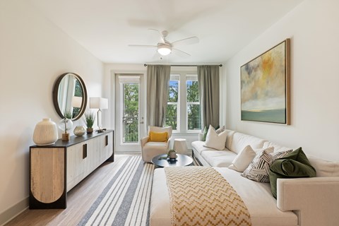 A living room with a white couch, a rug, and a painting on the wall.
