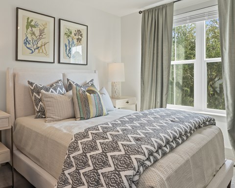 A bedroom with a large bed and two framed pictures on the wall.