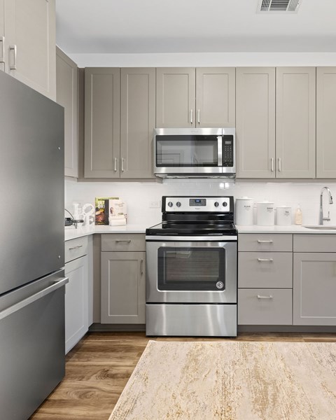 A modern kitchen with a stainless steel refrigerator, microwave, oven, and cabinets.
