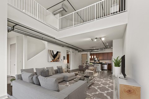 A living room with a grey couch and a television on a wooden stand.