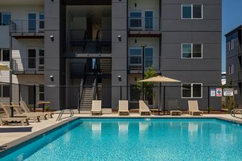A swimming pool in front of a grey apartment building.