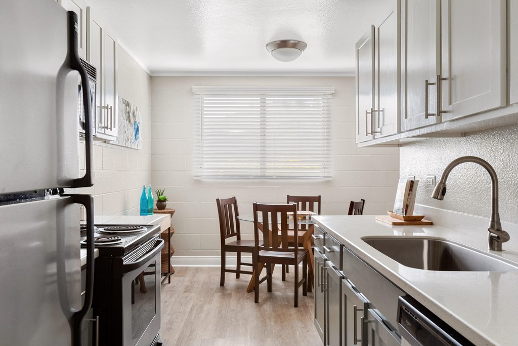 model kitchen, refrigerator and stove on the left with sink on the right looking toward the dining area