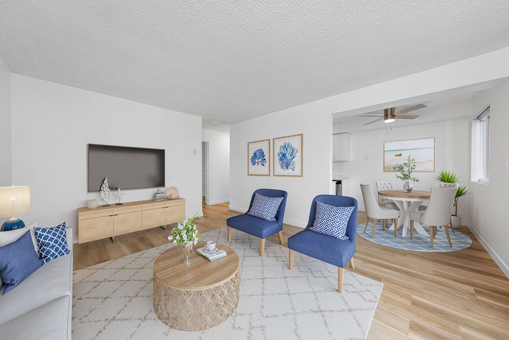 A living room with a television, two chairs, a coffee table, and a dining table.