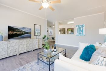 A living room with a white couch and a glass coffee table.