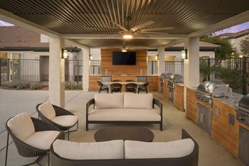 A patio with a couch, chairs, and a grill.