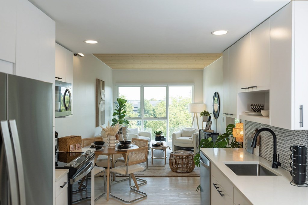 A modern kitchen with a dining area in the background.