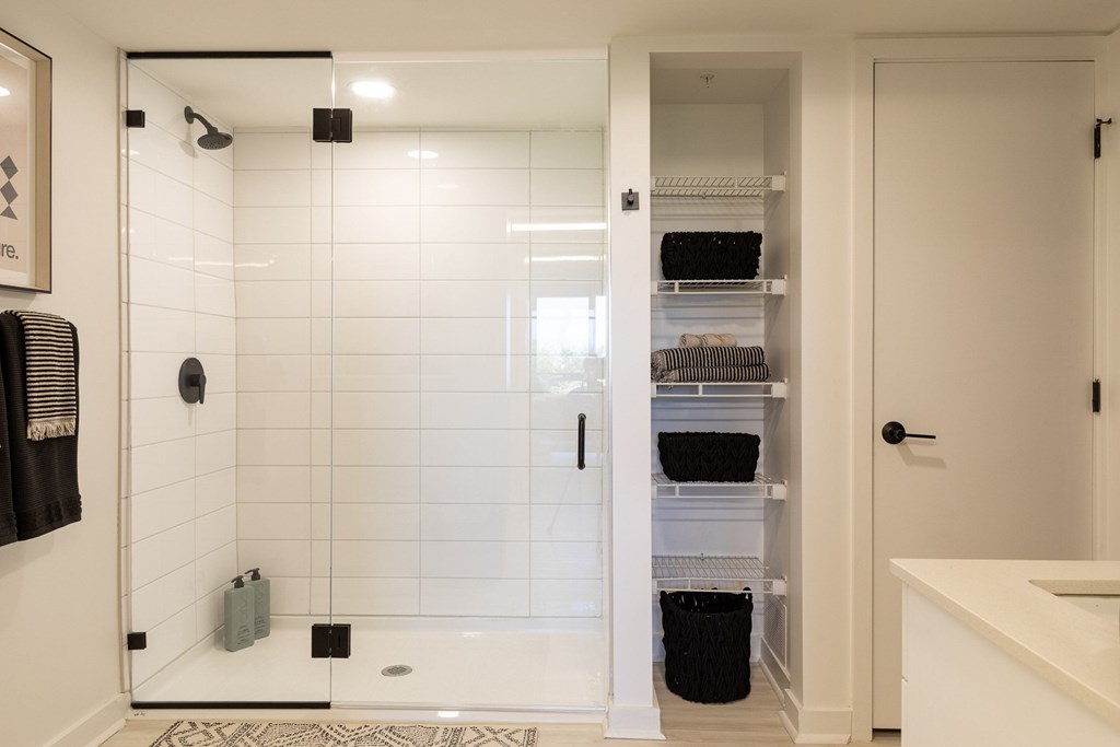 A white bathroom with a walk in shower and a white door.