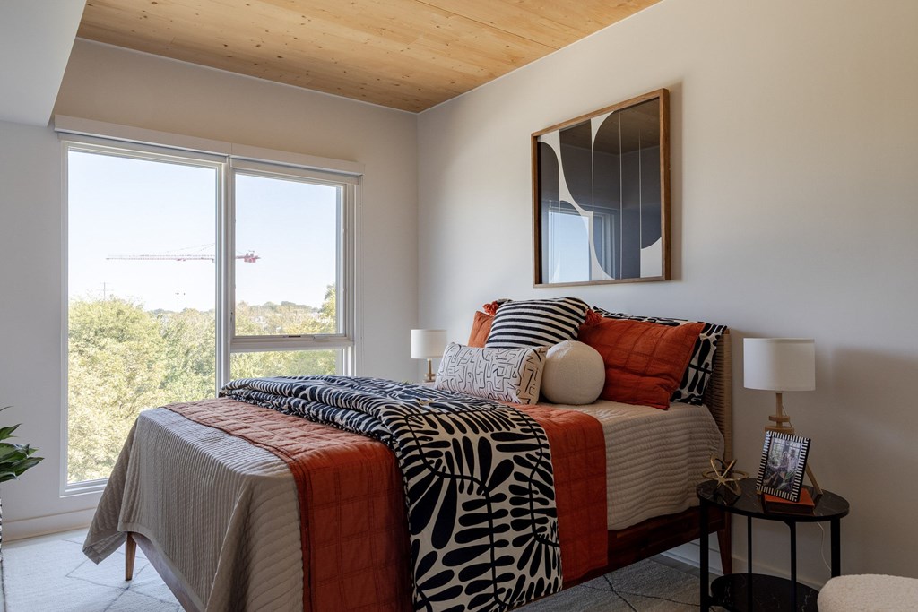 A bedroom with a bed, a nightstand, and a window.