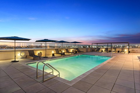 A swimming pool on a rooftop with a sunset in the background.