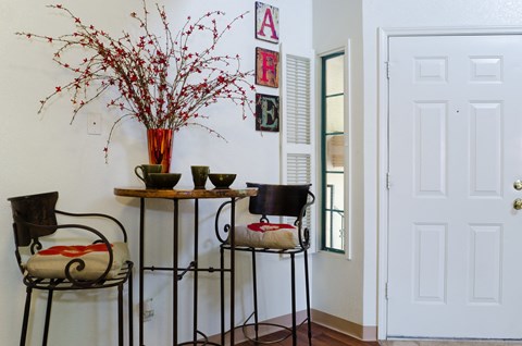 a dining room with two chairs and a table and a vase of flowers
