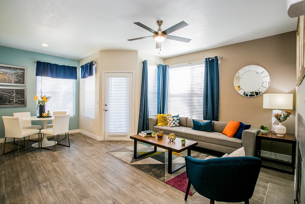 A living room with a grey couch, a blue chair and a wooden floor.