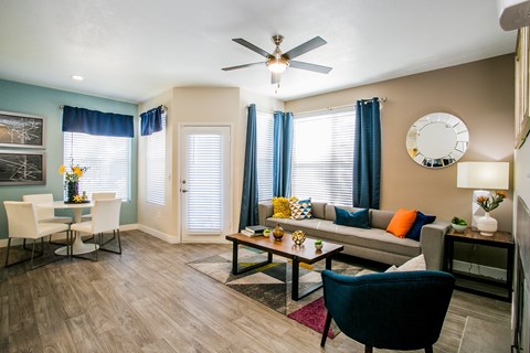 A living room with a grey couch, a blue chair and a wooden floor.