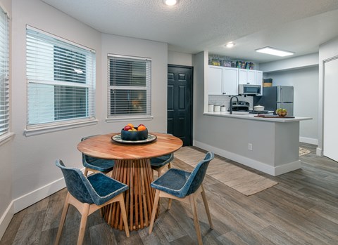 A kitchen with a table and chairs in the foreground and a refrigerator in the background.