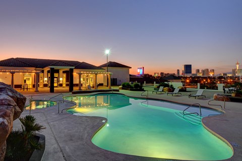 A swimming pool with a lit up building in the background.