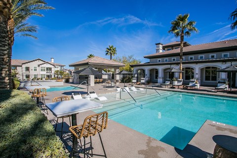 A pool with chairs and a table in front of a house.