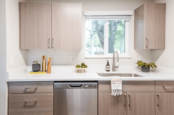 A modern kitchen with wooden cabinets and a stainless steel dishwasher.