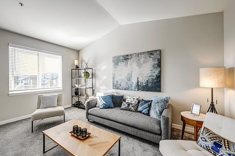 A living room with a grey couch, a wooden coffee table, and a large painting on the wall.