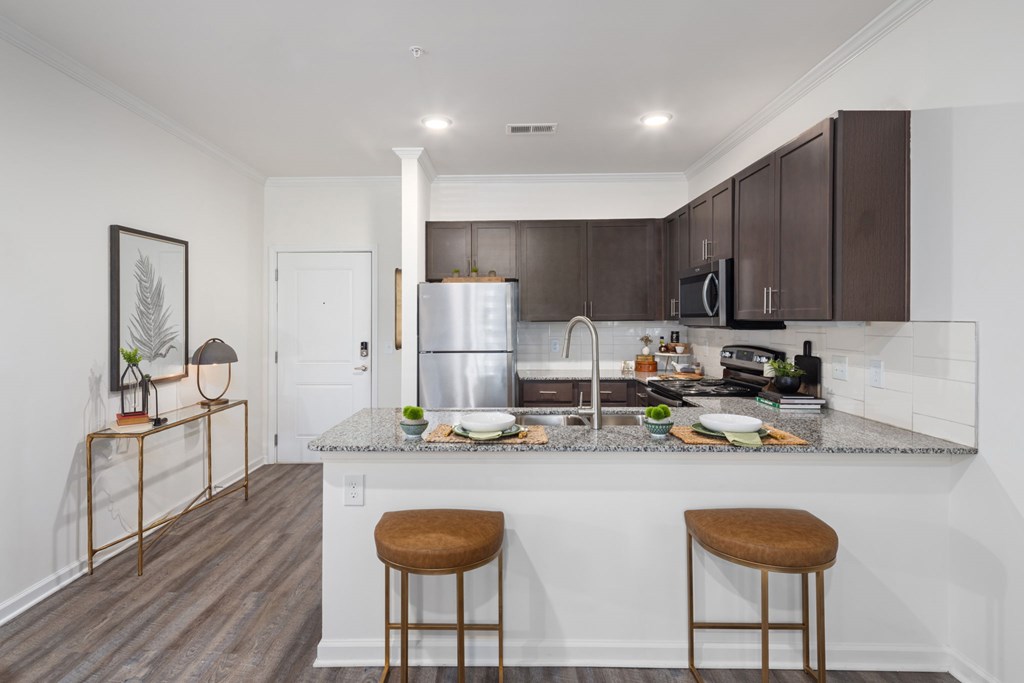 A kitchen with a granite countertop and two bar stools.