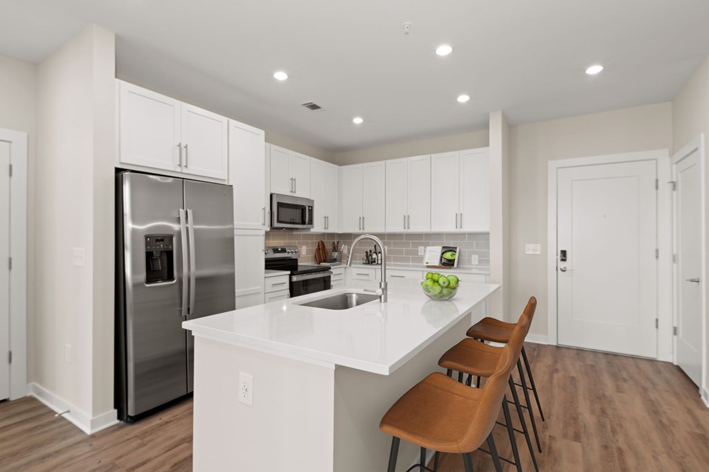 A kitchen with white cabinets and a wooden chair.