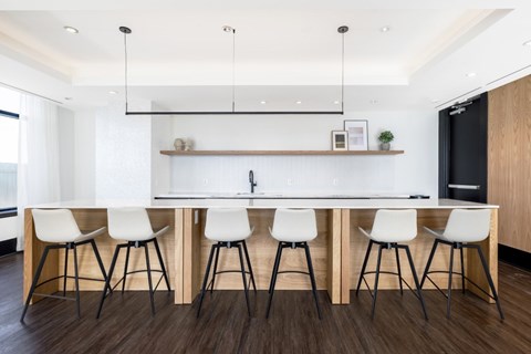 A modern kitchen with white chairs and a wooden table.