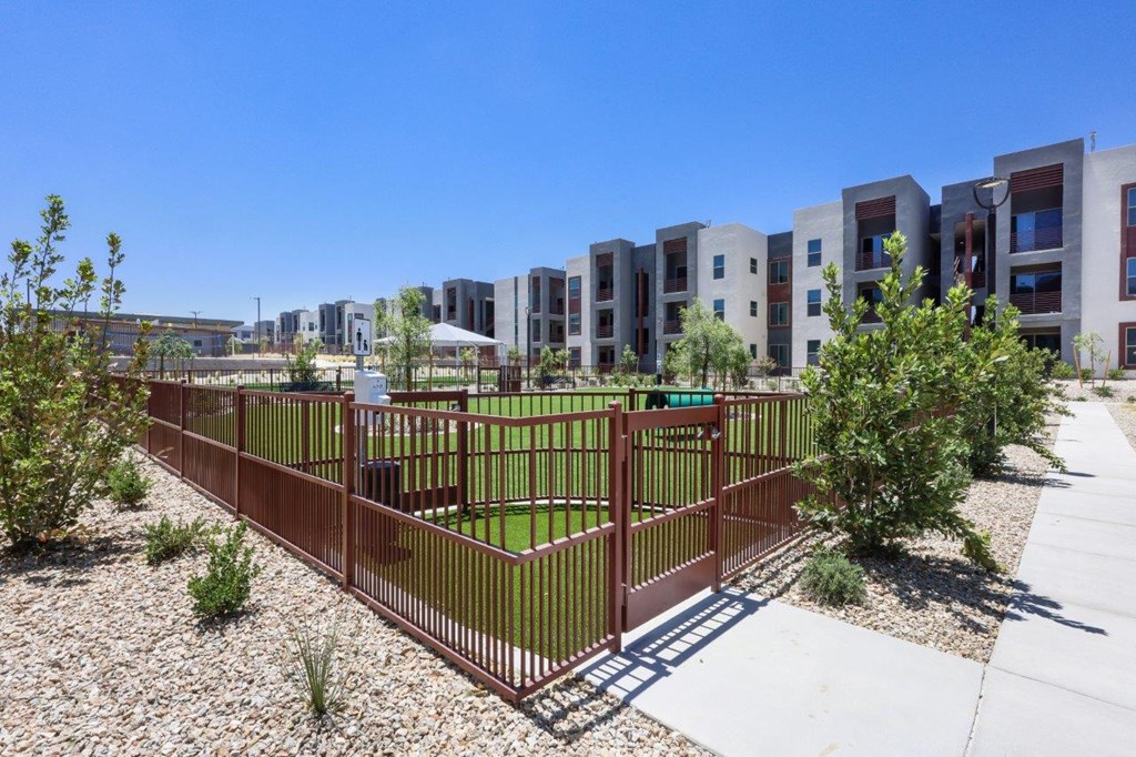 A fenced green space in front of apartment buildings.