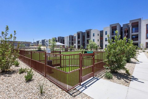 A fenced green space in front of apartment buildings.