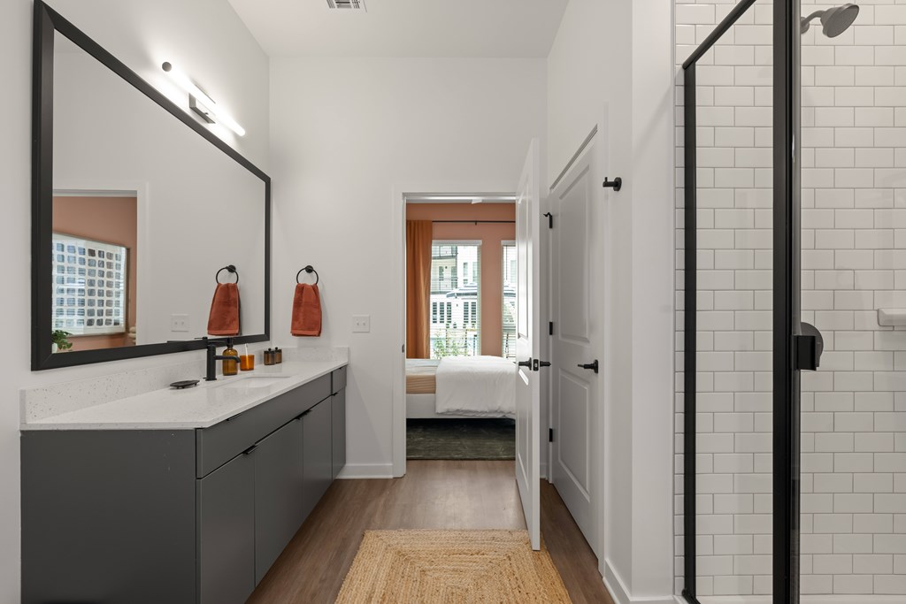 A bathroom with a white tile wall and a large mirror.