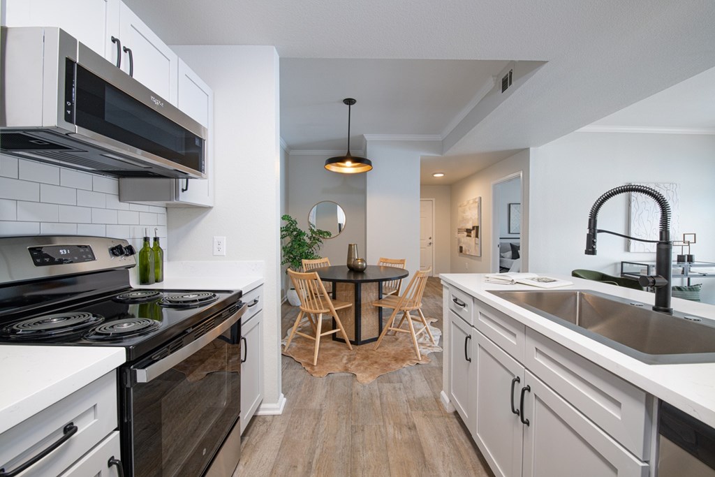 A modern kitchen with a black stove top oven and white cabinets.