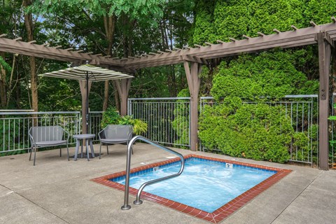 A small pool surrounded by a fence and a pergola.