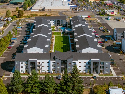 A large white building with a green roof in the middle of a parking lot.