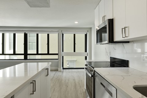 A modern kitchen with white cabinets and a black stove top oven.