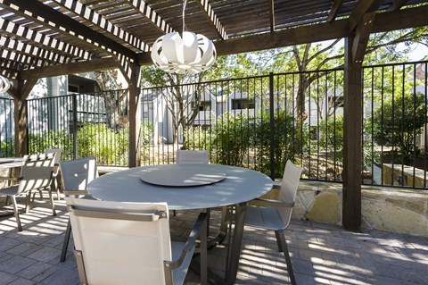 a patio with a table and chairs under a pergola