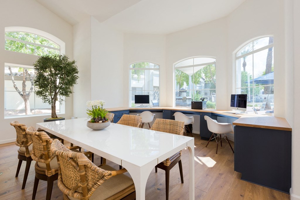 a large white table with wicker chairs sits in the middle of a room with white walls