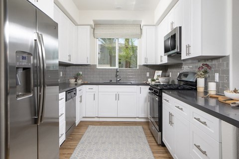 A modern kitchen with white cabinets and a black countertop.