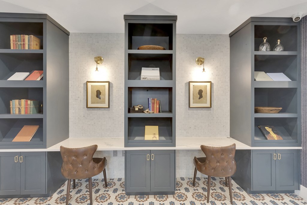 A room with grey bookshelves and two chairs.