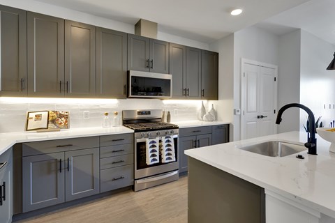 A modern kitchen with a stainless steel oven and dark grey cabinets.