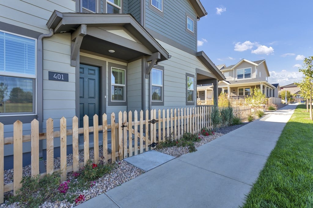 a sidewalk in front of a house with a fence