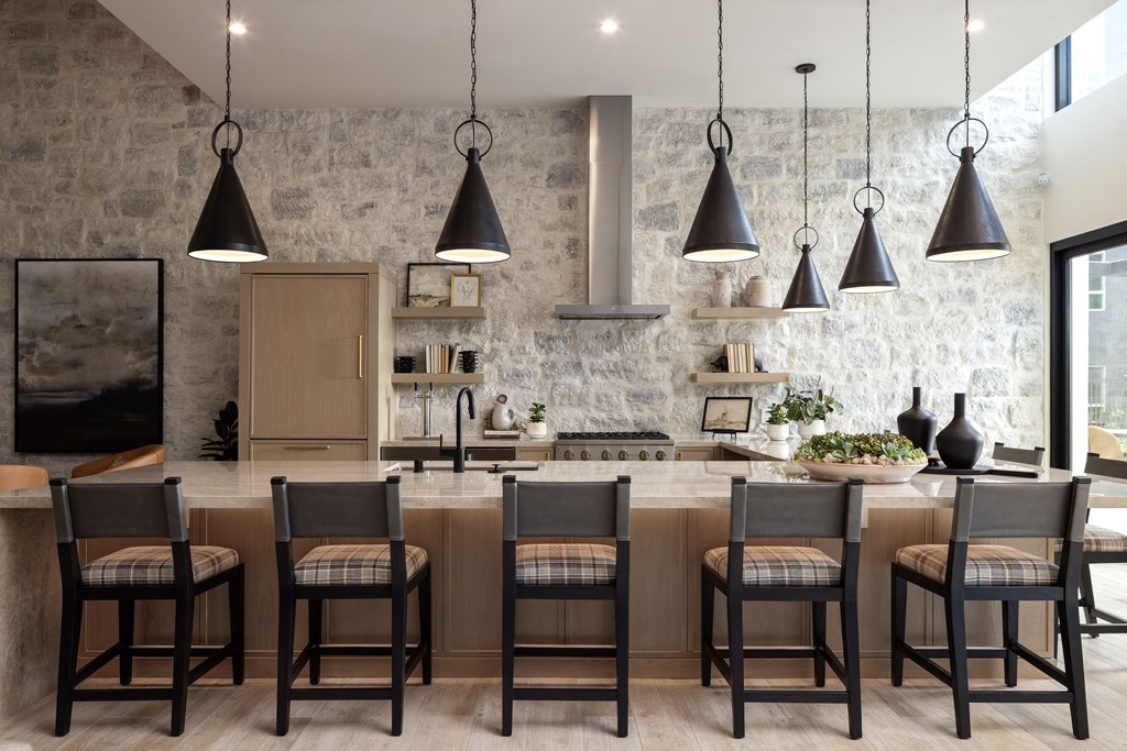 a kitchen with a large island with chairs and pendant lights