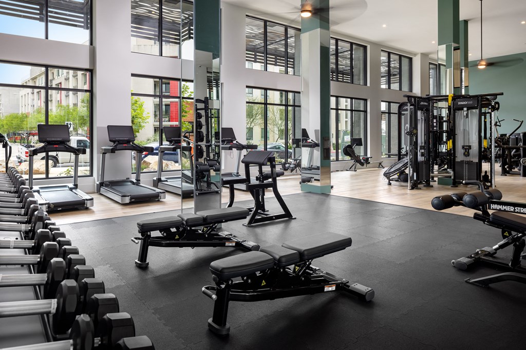 a gym with treadmills and other exercise equipment in a building with windows