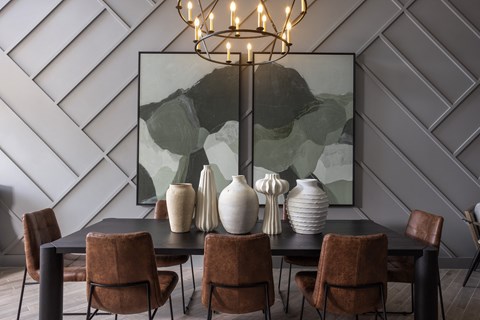 a dining room with a black table and chairs and a large painting
