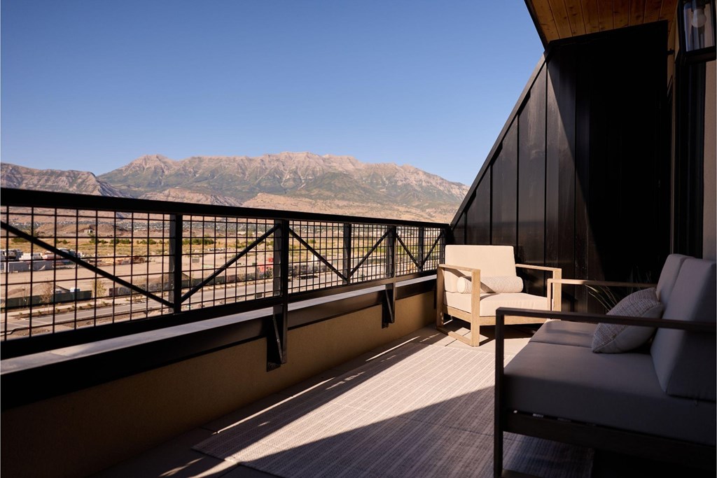 A balcony with a couch and a chair overlooking a mountain range.