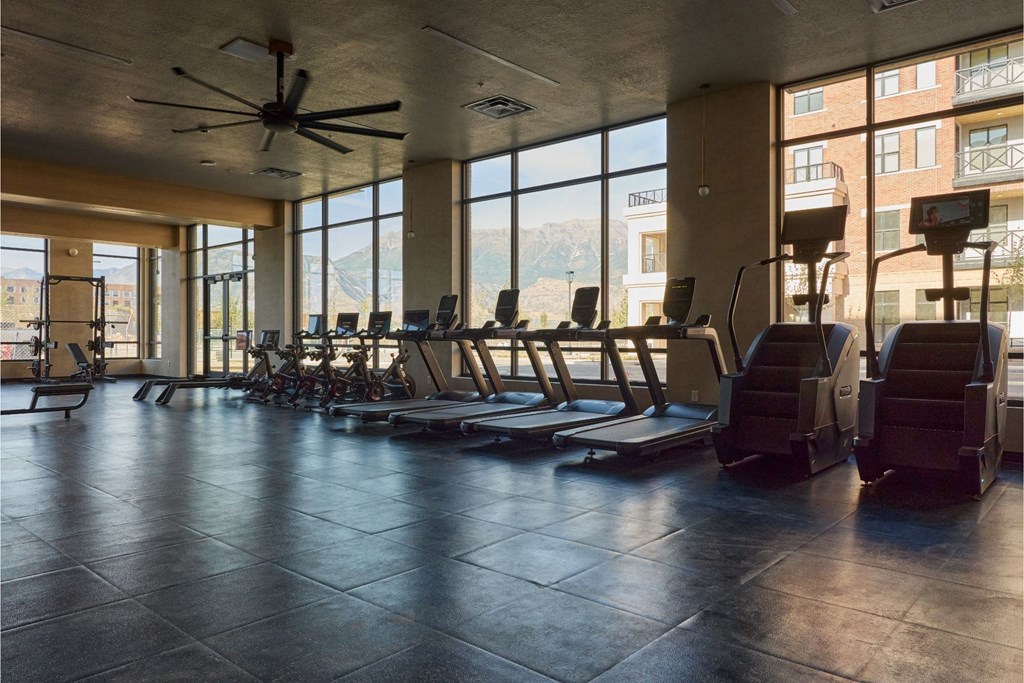 A gym with treadmills, exercise bikes, and a fan.