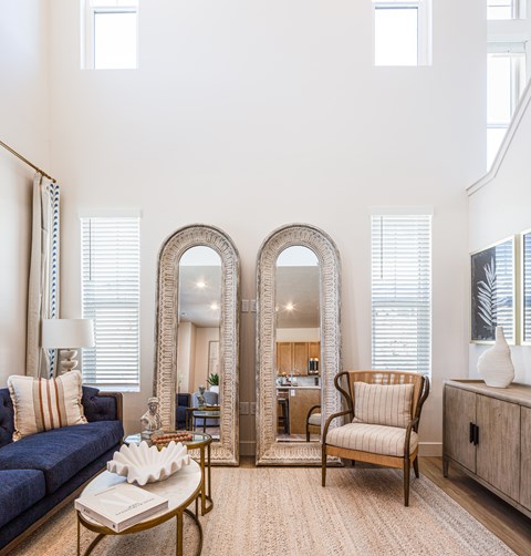 A living room with a sofa, a chair, a coffee table, and two mirrors.