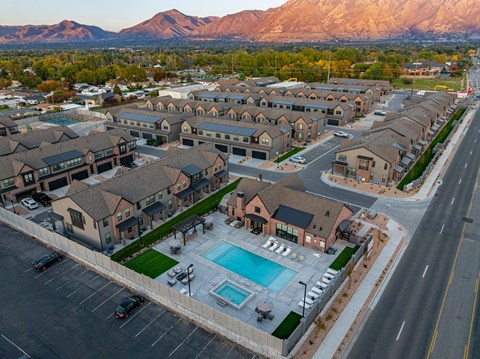 A large residential complex with a swimming pool and a mountain in the background.