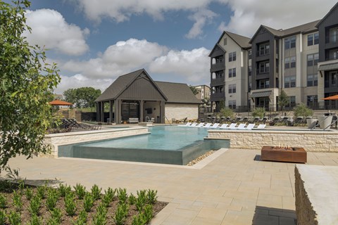 A pool surrounded by a patio and a building in the background.