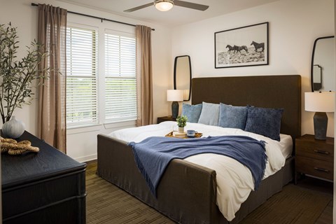 A bedroom with a bed, nightstand, and a ceiling fan.