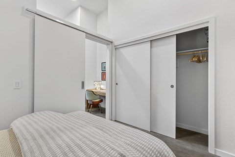 A bedroom with a bed and a desk in the other room.
