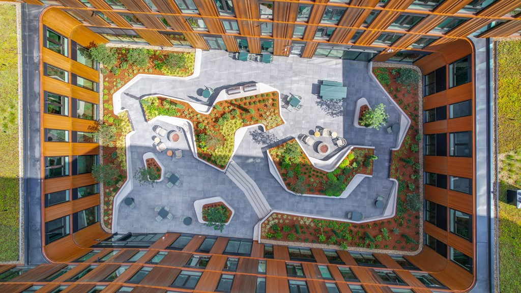 A top-down view of a courtyard surrounded by buildings with a green roof.