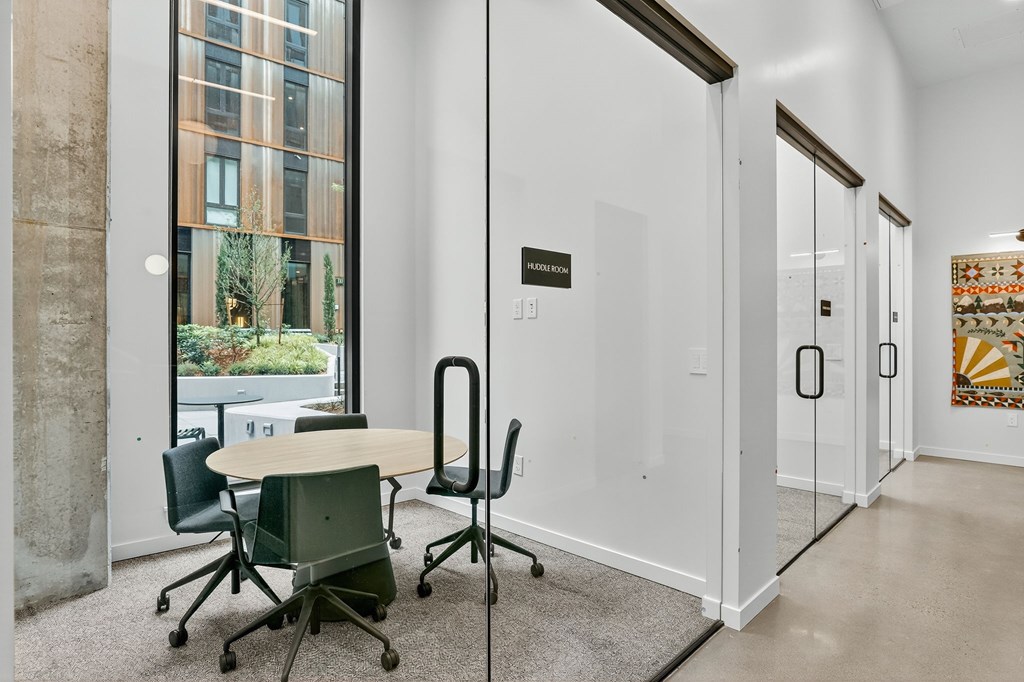 A conference room with a table, chairs and a glass wall.